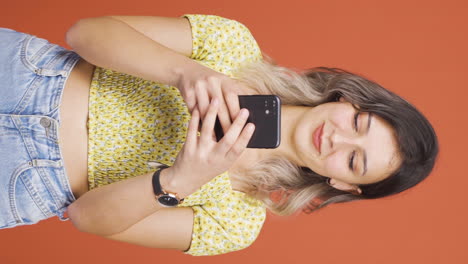 Vertical-video-of-The-young-woman-looking-at-the-phone-is-happy.